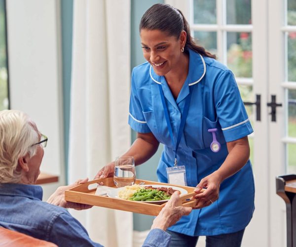 female-care-worker-in-uniform-bringing-meal-on-tra-2022-04-04-21-27-31-utc-1536x1024